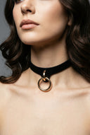 Black leather bdsm collar with gold ring worn around the neck of a woman
