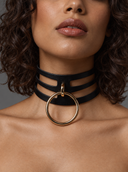 A close-up of a model wearing a black multi-strand choker necklace with a large polished gold ring at the center.